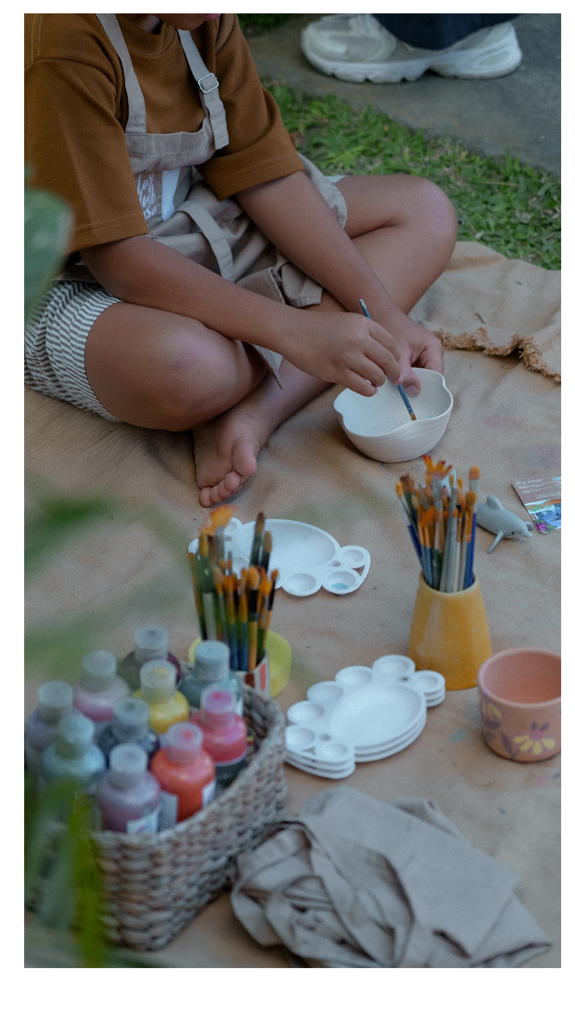 Child painting pottery at a market activity